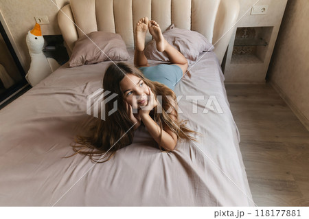A girl is laying on a bed with her head on her hand. She is looking up at the ceiling. A girl is laying on a bed with her head on her hand. She is looking up at the ceiling. 118177881