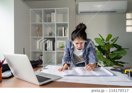 Engineer analyzing blueprints with focus in modern office 118178517