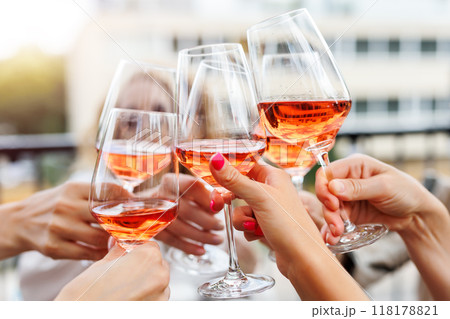 Close-up many female woman hands hold clinking rose wine glass celebrate toast party terrace warm sunset sun background. Girl friend enjoy drink champagne cocktail bachelorette event outdoor cafe bar 118178821