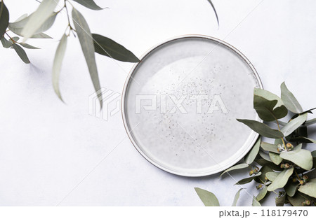 An empty plate with eucalyptus branches on a light background. Festive table setting. Top view An empty plate with eucalyptus branches on a light background. Festive table setting. Top view 118179470