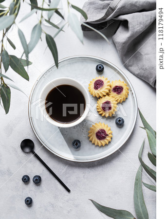Black coffee espresso in a cup with homemade berry cookies and blueberries on a light background Black coffee espresso in a cup with homemade berry cookies and blueberries on a light background 118179494