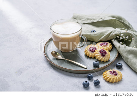 Cappuccino or latte with milk foam in a cup with homemade berry cookies and blueberries  118179510
