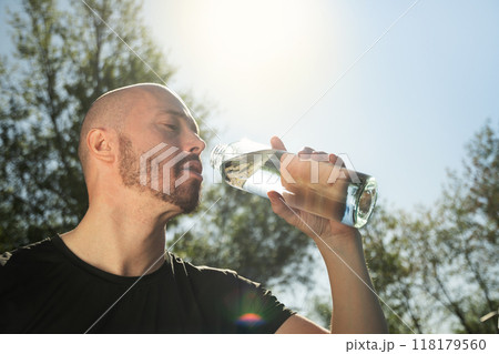 Athletes handsome man drinking water after active workout on outdoor sports ground. Water balance for heat season. Close up. 118179560