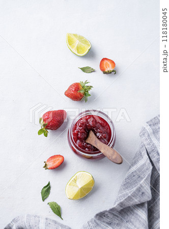 Strawberry jam in a jar on a light background with fresh berries.  118180045
