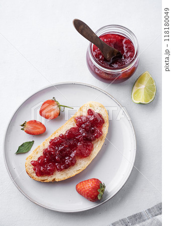 Strawberry jam on a piece of bread on a plate on a blue background with fresh berries and jar  118180049