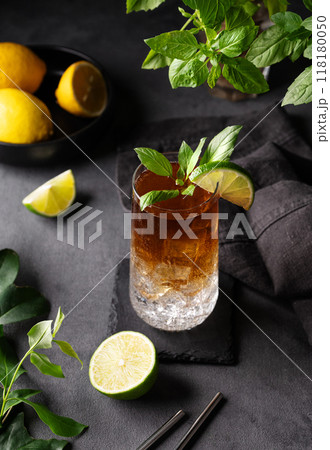 Coffee brew with tonic, ice and lime in a tall glass on a dark background with citrus fruit and herb 118180050