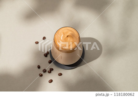 Dalgona coffee. Whipped instant coffee in a glass  with beans and shadow on green background. 118180062
