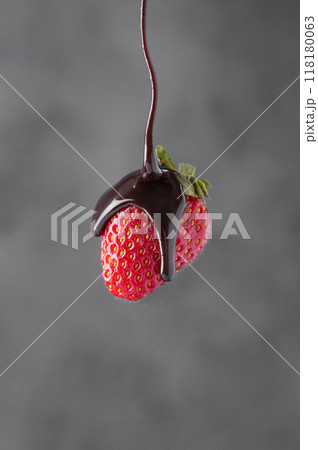 Chocolate flows on fresh juicy strawberries on a dark blurry background.  118180063