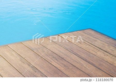 Empty wooden tabletop in front of a swimming pool with blue tiles.  118180070