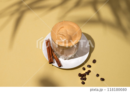 Dalgona coffee. Whipped instant coffee in a glass on a saucer with cinnamon sticks Dalgona coffee. Whipped instant coffee in a glass on a saucer with cinnamon sticks 118180080