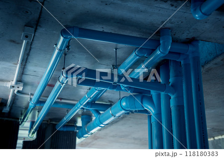 A bright blue pipes attached to a solid concrete wall 118180383