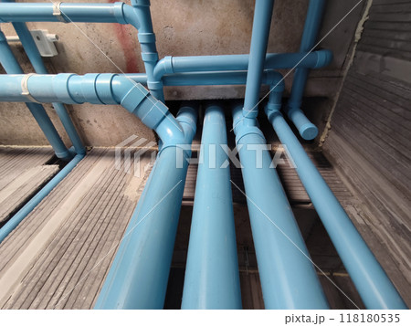 A bright blue pipes attached to a solid concrete wall A bright blue pipes attached to a solid concrete wall 118180535