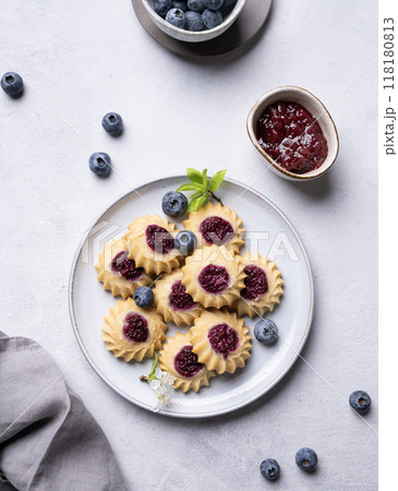 Delicious kurabye cookies with berry filling on a blue background with blueberries and jam. 118180813