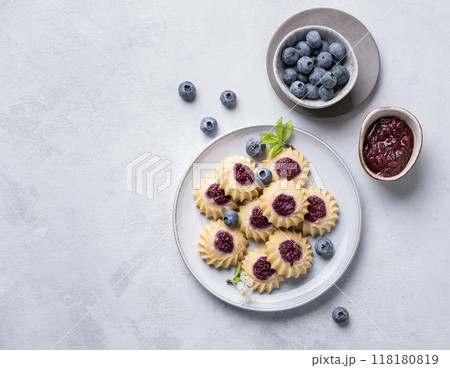 Delicious kurabye cookies with berry filling on a blue background with blueberries and jam.  118180819