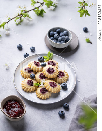 Homemade kurabye cookies with berry filling on a blue background with blueberries and jam 118180823