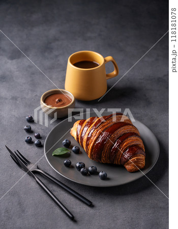 Freshly baked chocolate croissant with blueberries on a gray plate on a dark background Freshly baked chocolate croissant with blueberries on a gray plate on a dark background 118181078