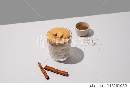 Dalgona coffee. Whipped instant iced coffee with soy milk in a glass with cinnamon sticks  118181086