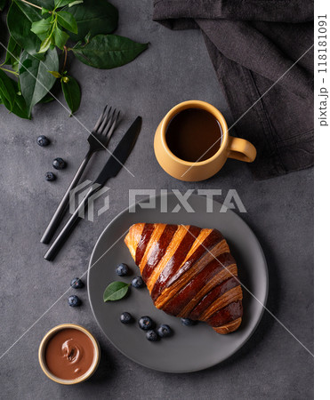 Freshly baked chocolate croissant with blueberries on a gray plate on a dark background Freshly baked chocolate croissant with blueberries on a gray plate on a dark background 118181091