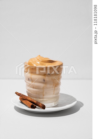 Dalgona coffee. Whipped instant iced coffee with milk in a glass with cinnamon sticks  118181098