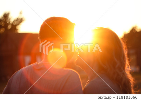 A heartwarming image of a couple's silhouettes against a vibrant sun setting or rising in the background. The scene conveys themes of love, hope, and happiness. Blurred, out of focus 118181666