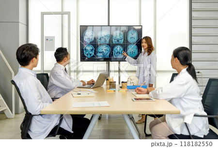 Young asian doctor in white gown pointing at referencing image of brain scan displayed on a screen during a medical conference. The audience listening attentively with the presentation. Young asian doctor in white gown pointing at referencing image of brain scan displayed on a screen during a medical conference. The audience listening attentively with the presentation. 118182550