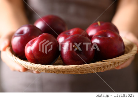 Red plum fruit in basket holding by woman hand, Healthy eating 118183025