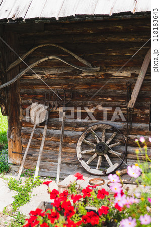 Antique garden tools and a cart wheel near a wooden village house on the street 118183643