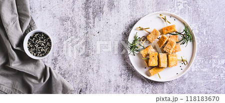 Pieces of delicious fried tofu soy cheese on skewers on a plate on the table top view web banner Pieces of delicious fried tofu soy cheese on skewers on a plate on the table top view web banner 118183670