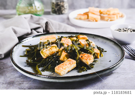Vegetarian fried tofu and seaweed salad on a plate on the table 118183681
