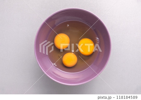 3 raw eggs in purple cup on grey background 3 raw eggs in purple cup on grey background 118184589