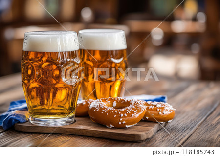 Two beer mugs on a wooden table with soft pretzels in the background 118185743