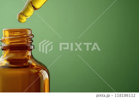 An elegant amber glass bottle stands isolated, with a dropper poised above. A golden drop of oil hangs delicately, ready to fall, capturing the essence of natural beauty and simplicity. 118186112