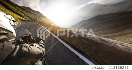 Detail of motorcycle handlebars. View from driver perspective, beautiful Alpine landscape in sunset light. Detail of motorcycle handlebars. View from driver perspective, beautiful Alpine landscape in sunset light. 118186231