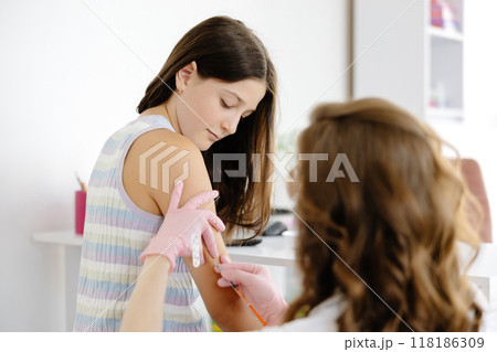 Female doctor, pediatrician injecting vaccine into teenage girl arm. Concept of preventive health care and vaccination for teenagers Female doctor, pediatrician injecting vaccine into teenage girl arm. Concept of preventive health care and vaccination for teenagers 118186309