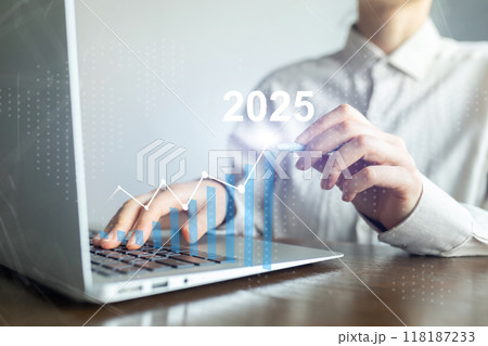 A person is typing on a laptop with a graph showing a line going up to 2025 A person is typing on a laptop with a graph showing a line going up to 2025 118187233
