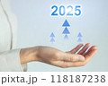 A hand holding a blue and white sign that says 2025 with three upward arrows 118187238