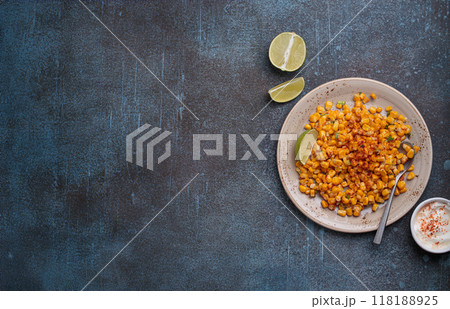 Plate of esquites mexican street corn salad with chili, mayonnaise, and lime on dark stone background Plate of esquites mexican street corn salad with chili, mayonnaise, and lime on dark stone background 118188925