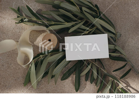 Summer branding stationery mock-up scene. Closeup of blank business card, invitation template on olive tree branches in sunlight. Limestone texture background. Mediterranean flat lay, top view. 118188986