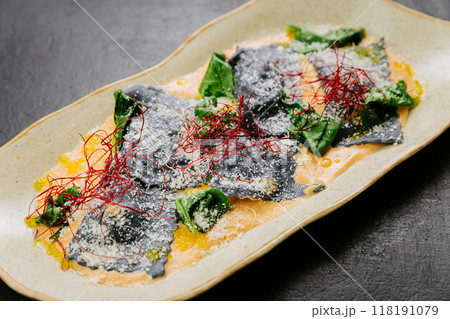 Gourmet squid ink ravioli with vibrant garnishes in a creamy sauce - an elegant and artistic dish Gourmet squid ink ravioli with vibrant garnishes in a creamy sauce - an elegant and artistic dish 118191079