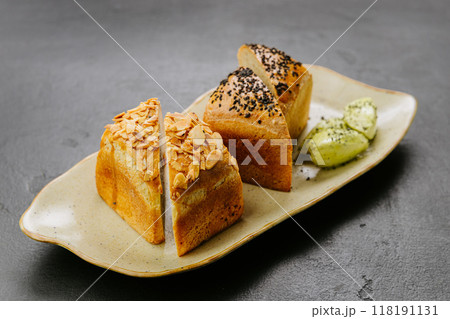 Freshly baked artisan bread slices with almonds and seeds, served with herbed butter on a plate 118191131