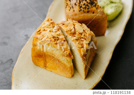 Freshly baked artisan bread slices with almonds and seeds, served with herbed butter on a plate 118191138