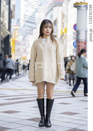 ニットのミニワンピースを着たカメラ目線で笑顔の20代の女性　 118192396