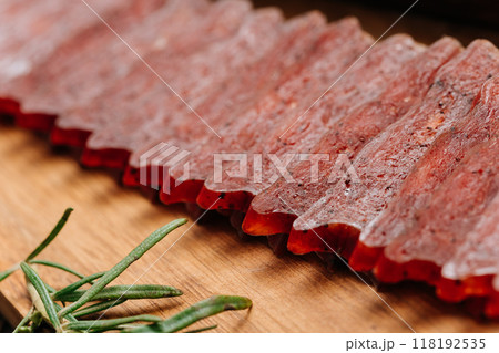 Sliced gourmet smoked salami on a wooden board with herbs, perfect for charcuterie boards and snacks Sliced gourmet smoked salami on a wooden board with herbs, perfect for charcuterie boards and snacks 118192535