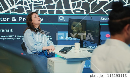 Young stressed call center operator communicating gps coordinates to the courier, working under pressure to give directions to the delivery truck. Employee consulting satellite map. Camera A. 118193118