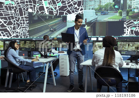 Indian supervisor handles express delivery orders through city traffic, working with his team to provide alternative routes via satellite navigation and CCTV footage. Gps tracking system. Indian supervisor handles express delivery orders through city traffic, working with his team to provide alternative routes via satellite navigation and CCTV footage. Gps tracking system. 118193186
