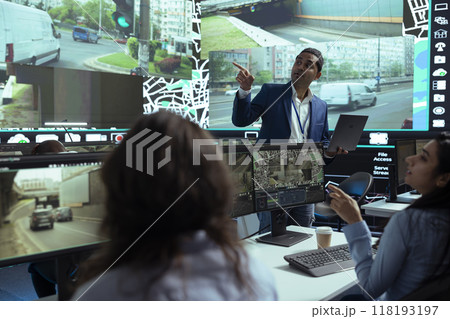 Indian team leader gives insight to his employees at shipping agency headquarters, people working on help couriers deliver their cargo in time. Operators monitoring traffic, gps tracking. 118193197