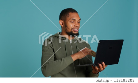 Happy man adding payment method on website using laptop, delighted to take advantage of promotions, studio background. Person thrilled to do internet shopping, typing credit card data, camera A Happy man adding payment method on website using laptop, delighted to take advantage of promotions, studio background. Person thrilled to do internet shopping, typing credit card data, camera A 118193205