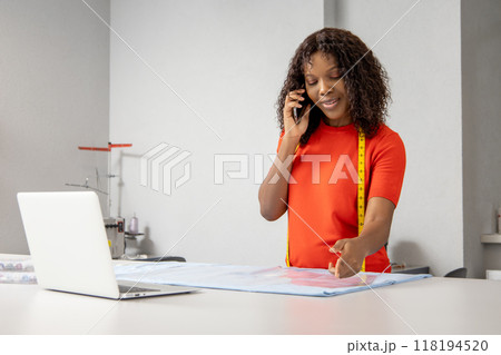 Woman tailor working at sewing workshop talking on phone 118194520