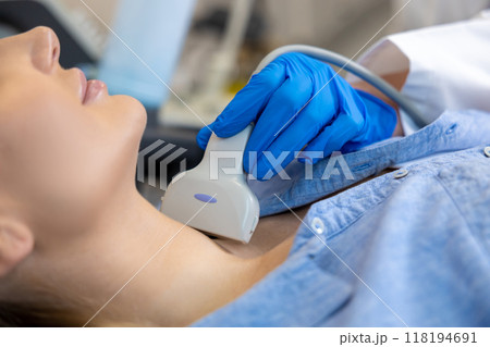 Close up of young woman having an ultrasonography procedure on her thyroid gland 118194691