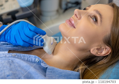 Young woman having an ultrasonography procedure on her thyroid gland 118194703